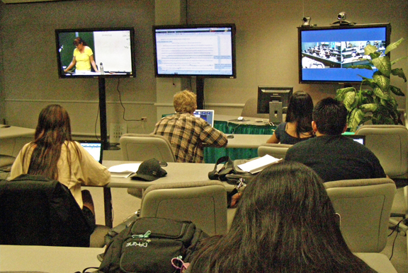 people in a classroom watching multiple monitors